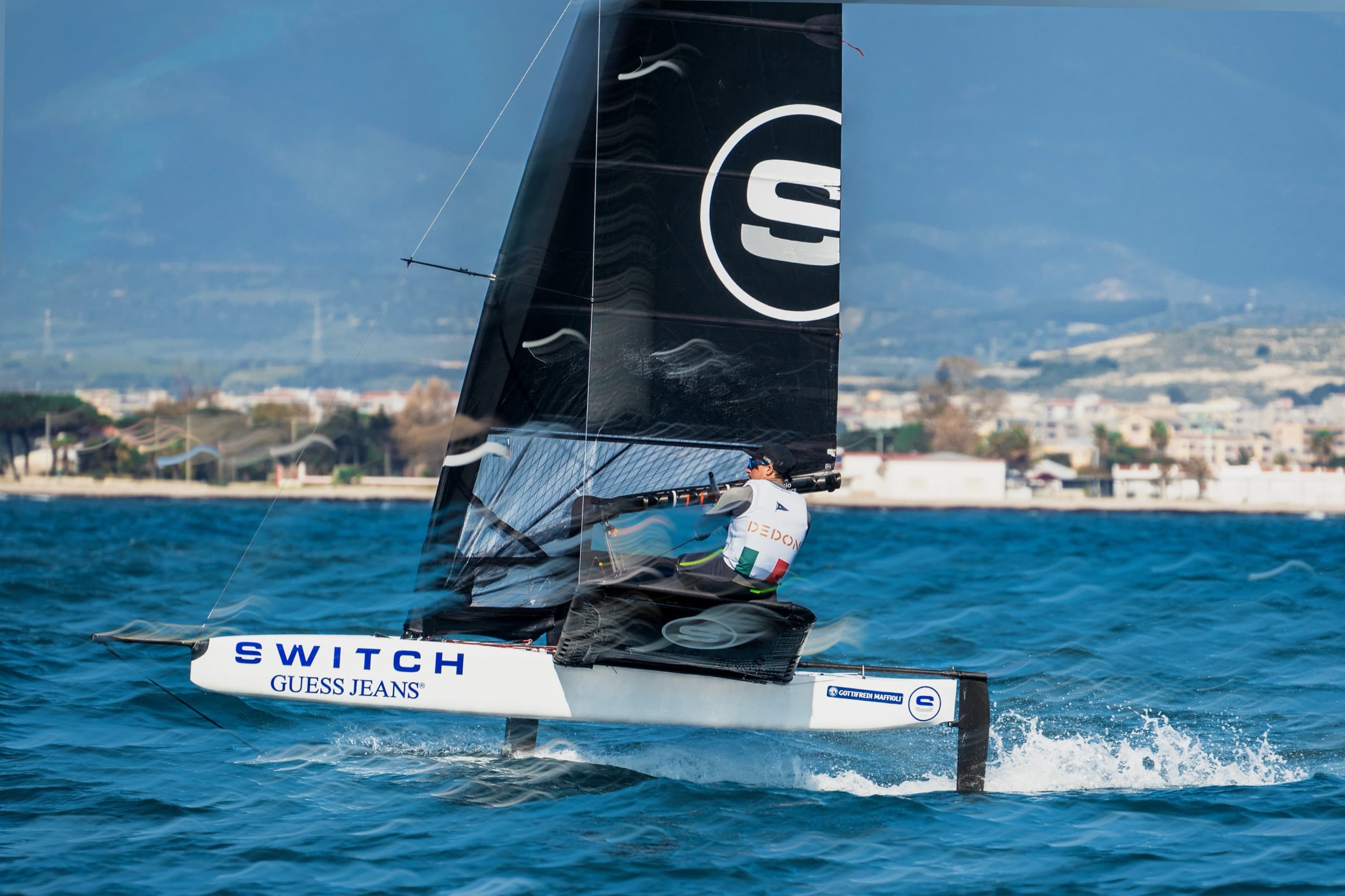 Switch sailor racing at speed with the crew hiking over the water.